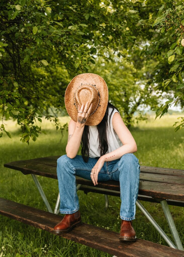 a woman wearing a straw hat sitting on a bench